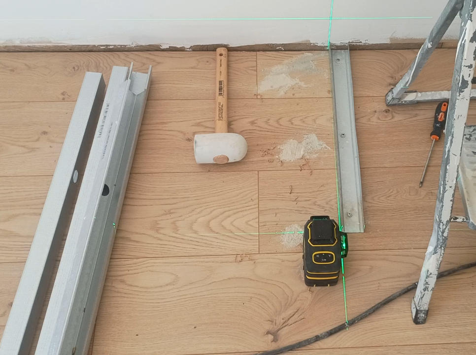 Pose de rails métalliques alignés au laser entre sol et plafond pour un dressing, sans traçage au crayon