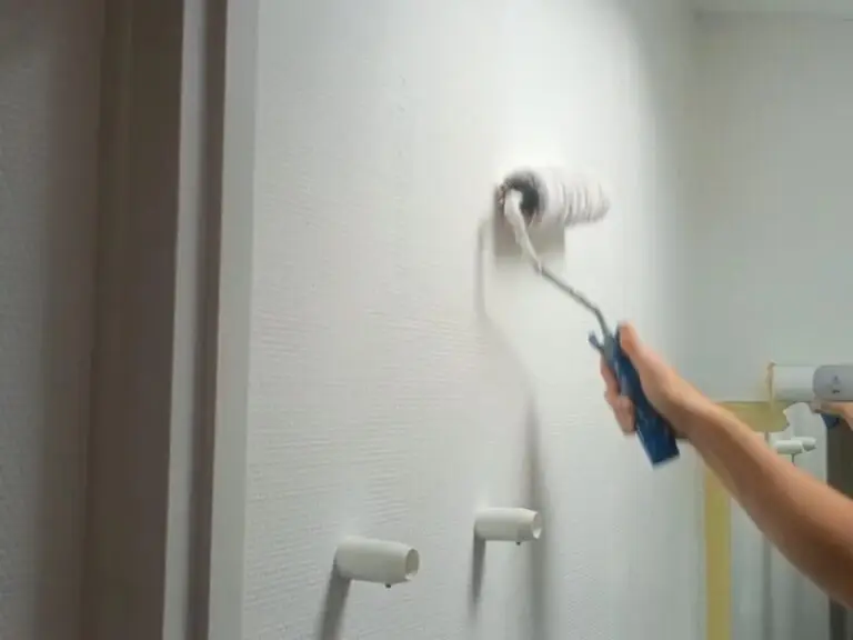 Application de peinture au rouleau sur le mur d’une salle de bain rénovée après un dégât des eaux sur La Rochelle