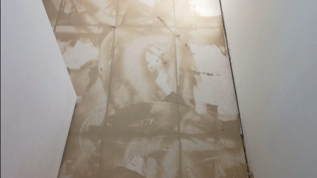 Application de joints hydrofuges gris clair entre des carreaux rectifiés 30x60 dans une salle de bain.