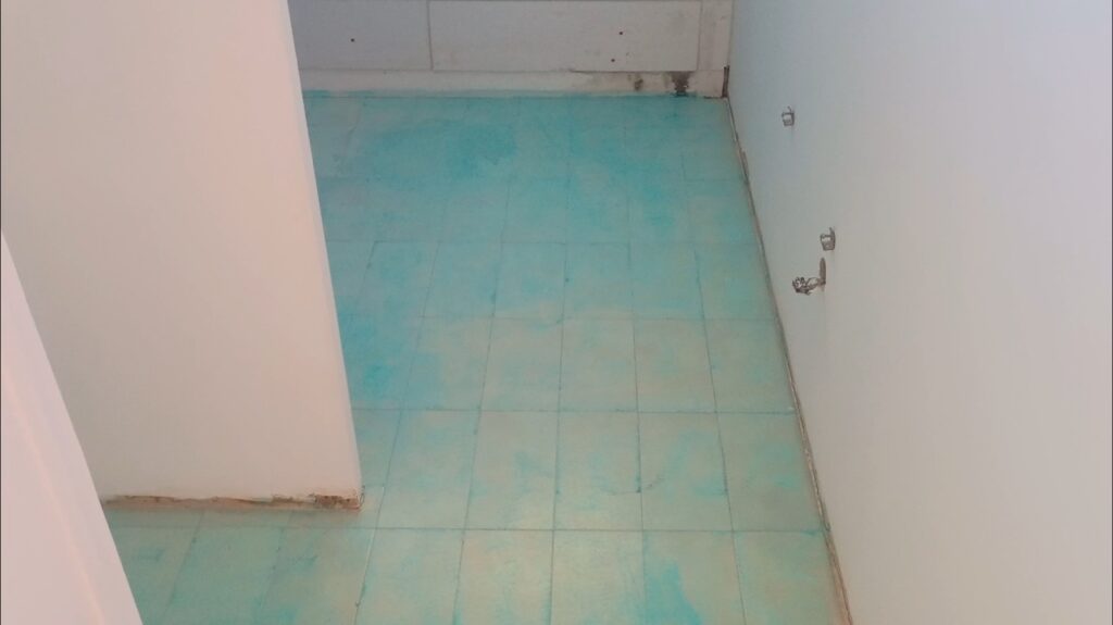 Application d’un primaire d’accrochage sur le sol avant la pose d’un carrelage rectifié 30x60 dans une salle de bain.