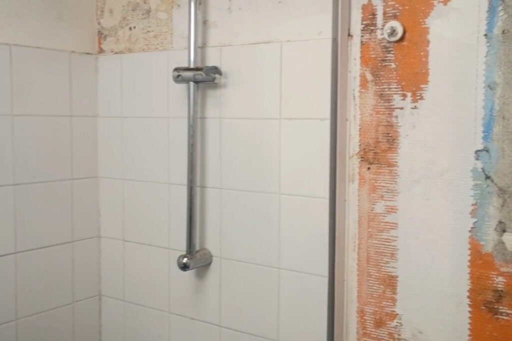 Mur de salle de bain sous combles après démontage du ballon d’eau chaude, des toilettes et des parois de douche suite à un dégât des eaux