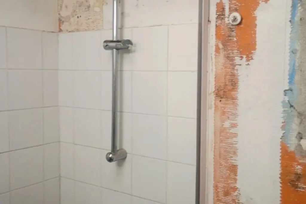Mur de salle de bain sous combles après démontage du ballon d’eau chaude, des toilettes et des parois de douche suite à un dégât des eaux