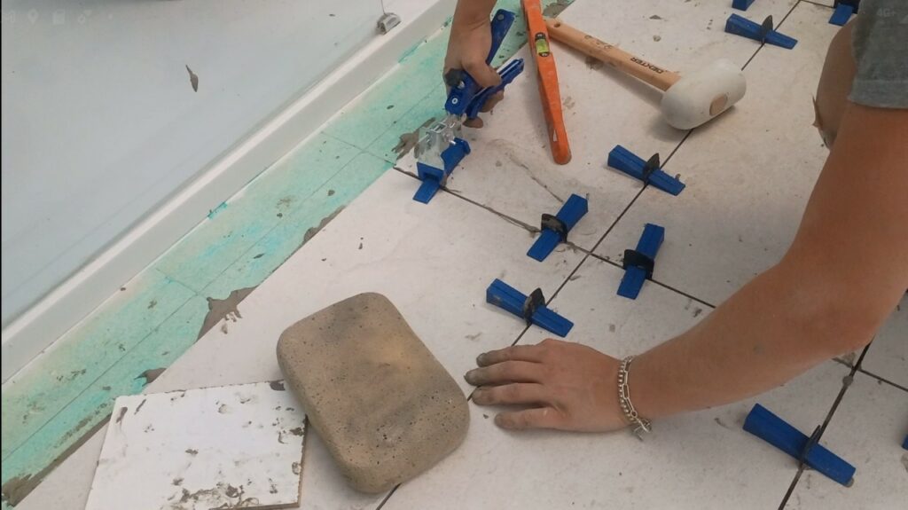 Retrait des cales de nivellement avec une pince sur un carrelage rectifié 30x60 dans une salle de bain.