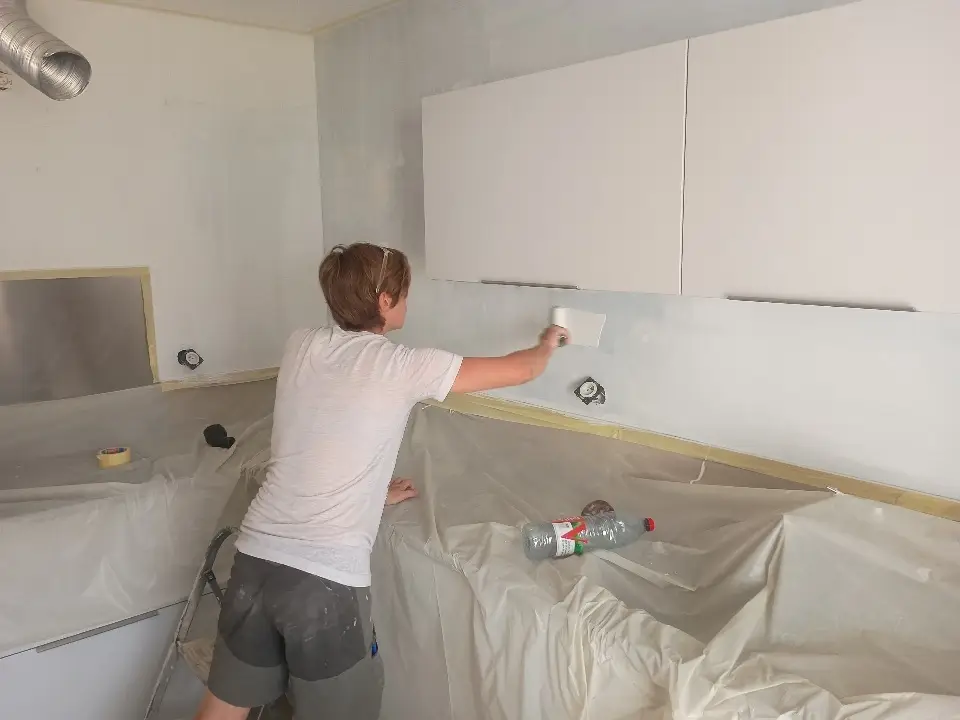 Pose d’une couche de primaire sur le mur de cuisine pour préparer la mise en peinture