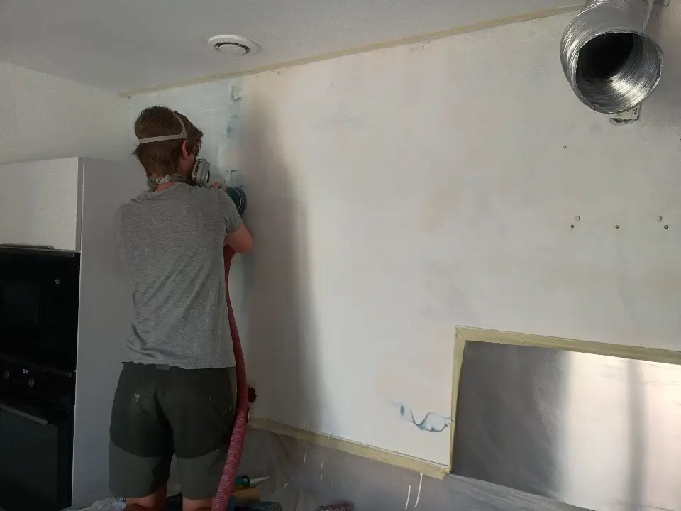 Ponçage des passes d’enduit afin d’obtenir une surface lisse avant peinture dans la cuisine