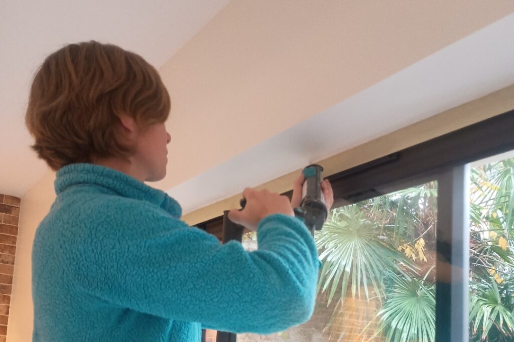 Artisan peintre à Rochefort posant un joint acrylique autour d’un cadre de fenêtre en PVC avant mise en peinture, lors d’une rénovation intérieure en Charente-Maritime.