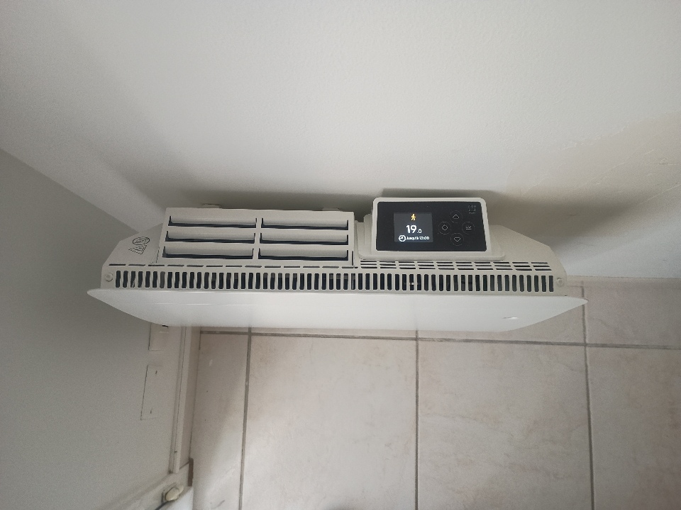 Radiateur électrique compact 1000 W dans une chambre avec écran digital affichant la température