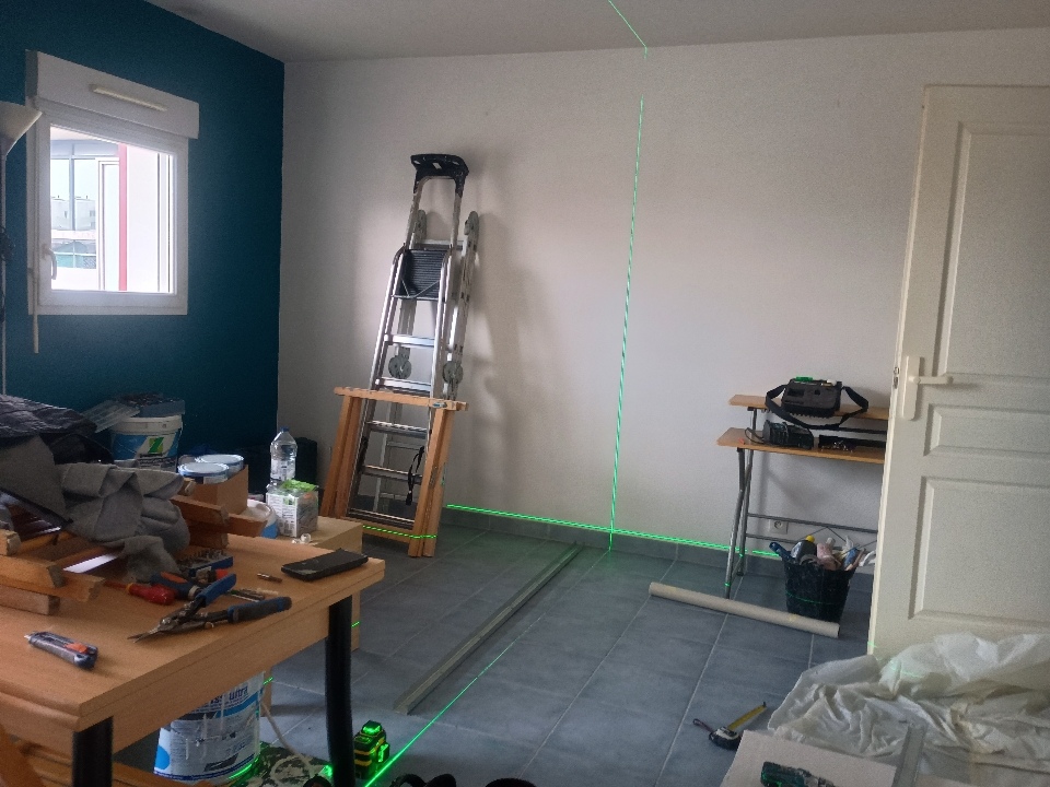 Artisan Aco Rénov réalisant une mesure au laser pour l’implantation d’une cloison dans un studio à La Rochelle.