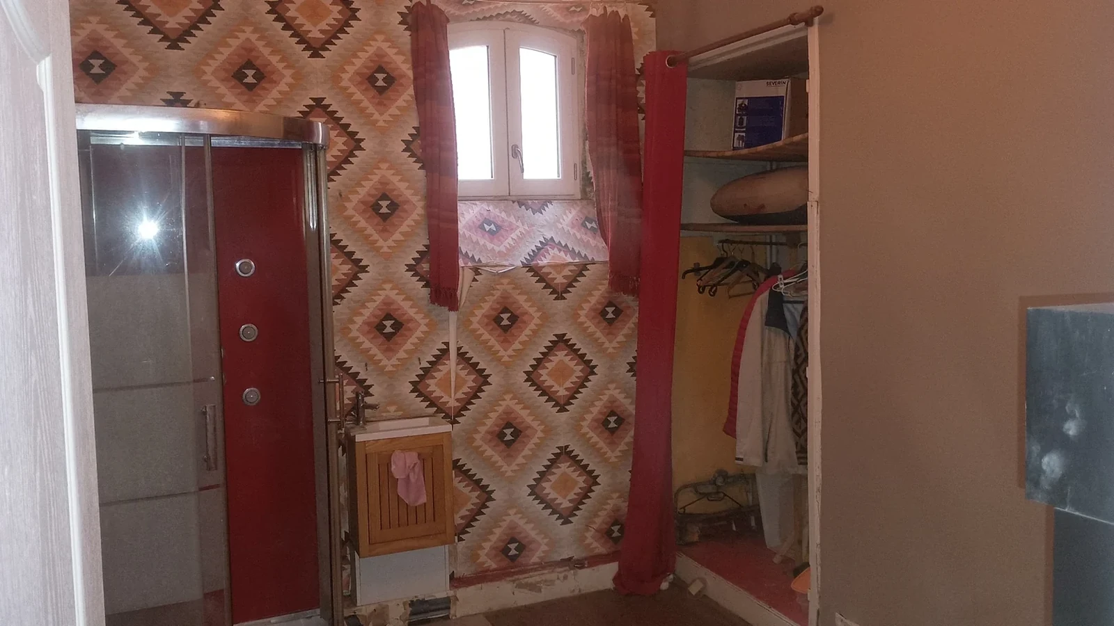 Ancienne salle de bains avec douche d'angle, papier peint et dressing avant rénovation intérieure à La Rochelle.