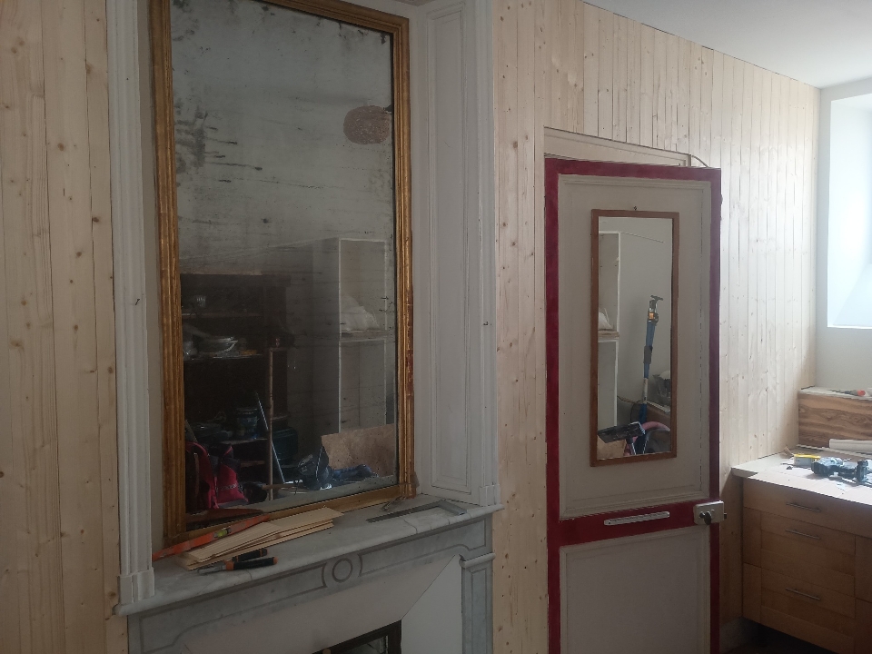 Mur entièrement habillé en lambris bois massif avec intégration d'une porte ancienne et d'une cheminée.