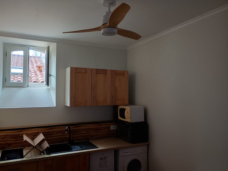 Cuisine rénovée équipée d'un ventilateur de plafond blanc avec pales imitation bois.