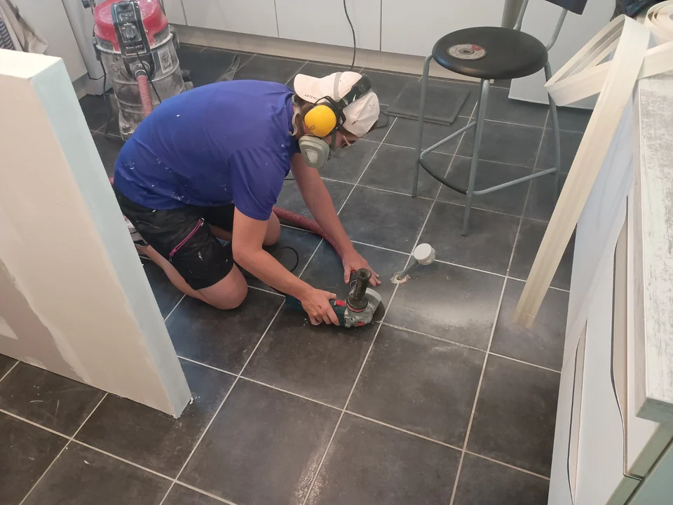 Artisan équipé réalisant des travaux de préparation au sol pendant une rénovation de cuisine