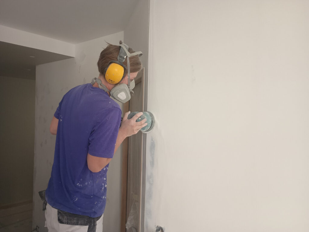 Ponçage d’un mur avant peinture dans un appartement à La Rochelle